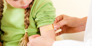 Child sitting while doctor applies band-aid to her arm